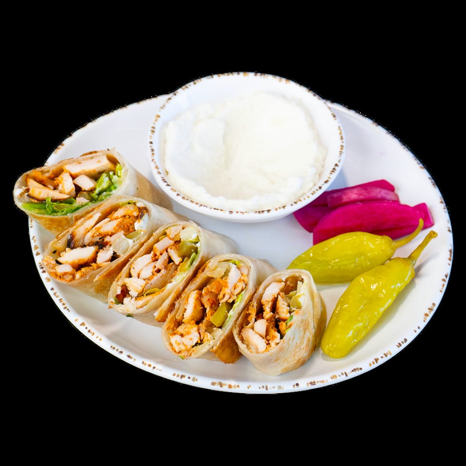 Chicken shawarma wraps with garlic sauce, pickled turnips, and yellow peppers on a white plate.