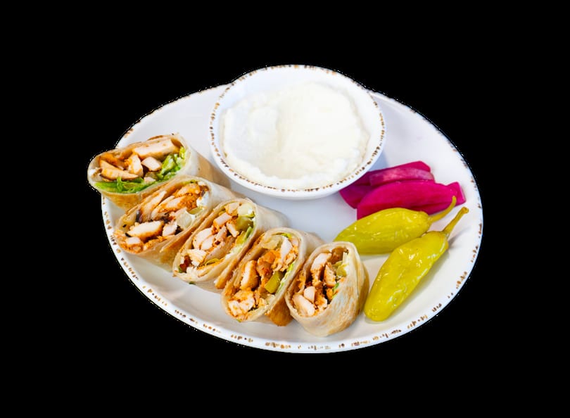 Chicken shawarma wraps with garlic sauce, pickled turnips, and yellow peppers on a white plate.