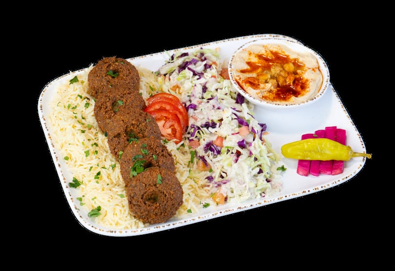 Falafel plate with rice, coleslaw, hummus, sliced tomatoes, pickled turnips, and a yellow pepper.