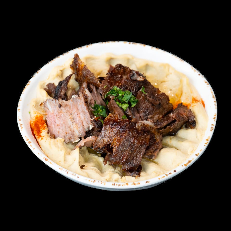 A bowl of creamy hummus topped with savory shredded meat, fresh parsley, and a sprinkle of paprika.