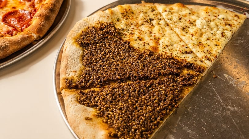 Two pizzas on metal trays, one pepperoni and one half za'atar, half cheese.